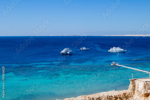 Fototapeta Naklejka Na Ścianę i Meble -  Dark blue clean bay water panorama on the Red Sea shore, spectacular landscape with resort yachts