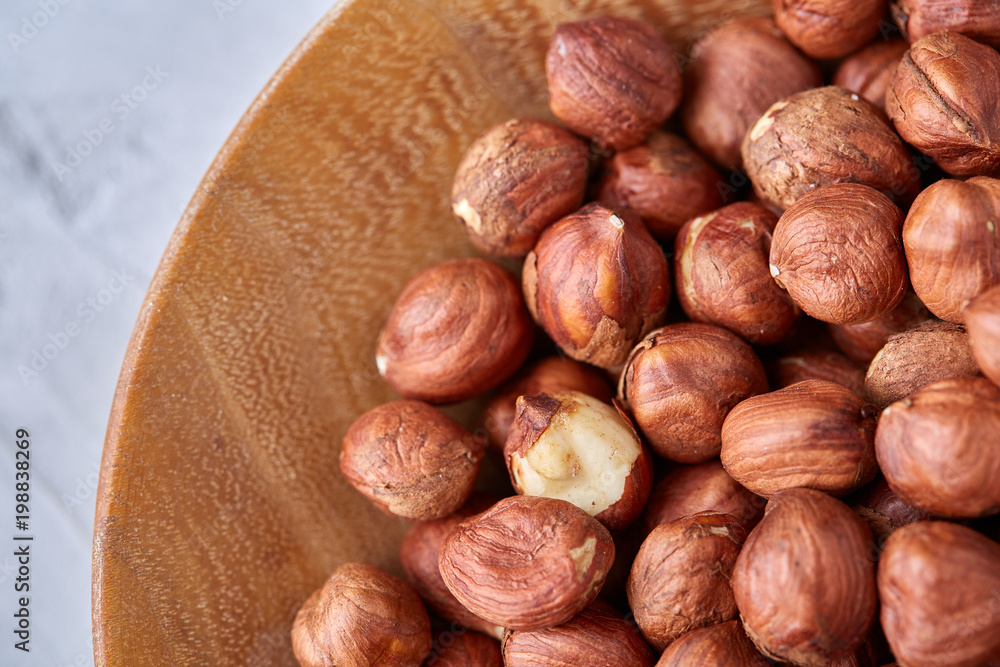 Hazelnuts in wooden bowl on wihite background with copy space, top view, selective focus. Hazelnuts in wooden bowl on wihite background with copy space, top view, selective focus.