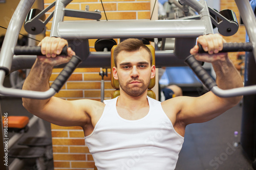 Man exercising at gym. Fitness athlete doing chest exercises on vertical bench press machine