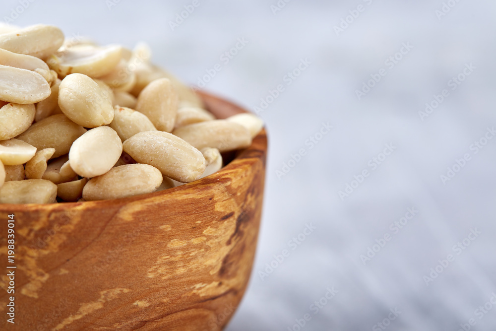 Peanuts in wooden plate isolated over white textured background, top view, close-up. Peanuts in wooden plate isolated over white textured background, top view, close-up.