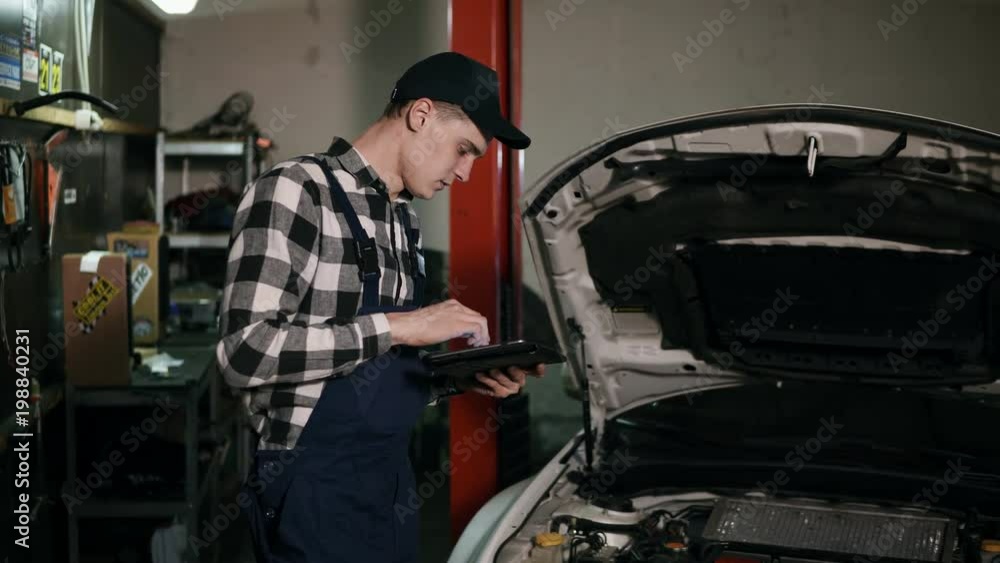 Mechanic inspects the car undercarriage way with a digital tablet Mechanic inspects the car undercarriage way with a digital tablet