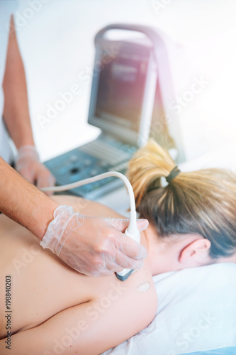 Doctor conducting ultrasound examination of patient's knee sonography in clinic