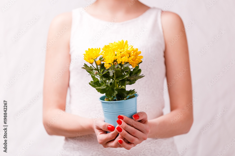 Image of woman holding pot of yellow flower