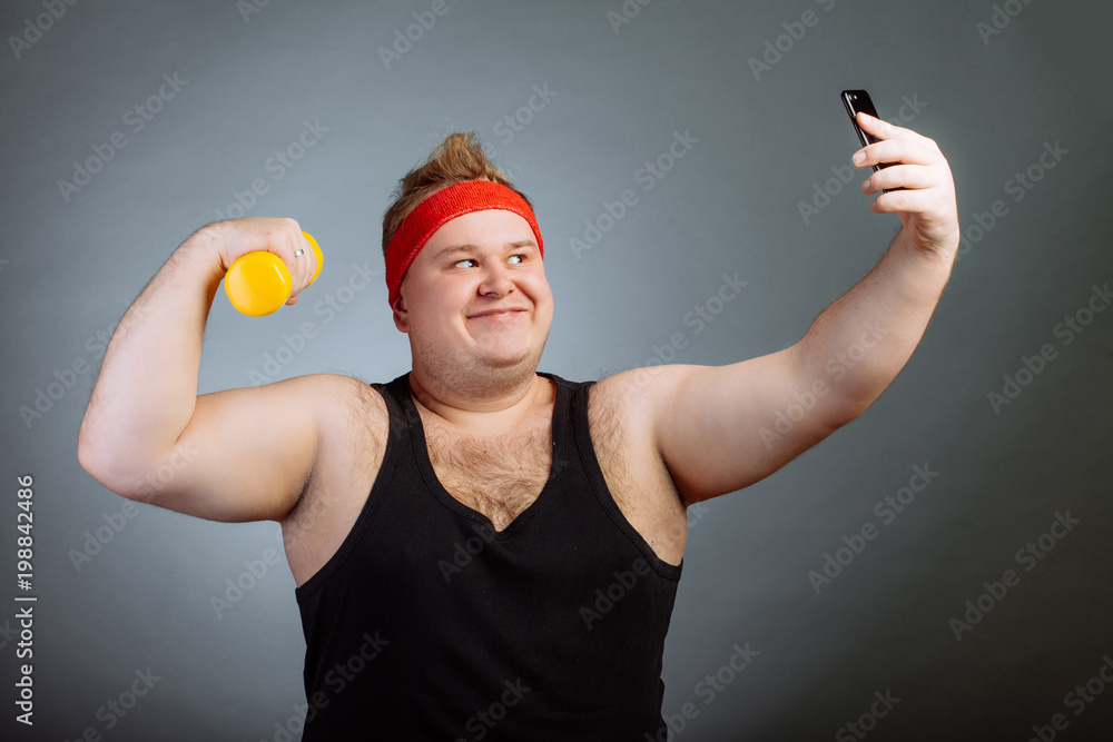 Funny smile fat man wearing black shirt with big belly, pumping biceps and  doing selfie on grey background Stock Photo | Adobe Stock