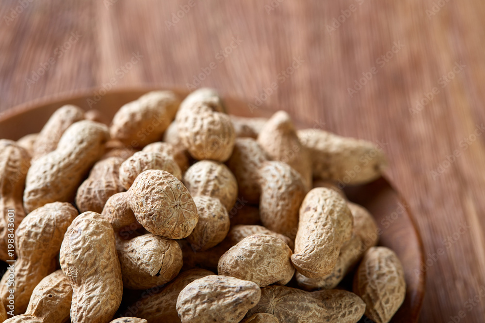 Unpeeled peanuts on a wooden background, top view, selective focus, shallow depth of field. Unpeeled peanuts on a wooden background, top view, selective focus, shallow depth of field.