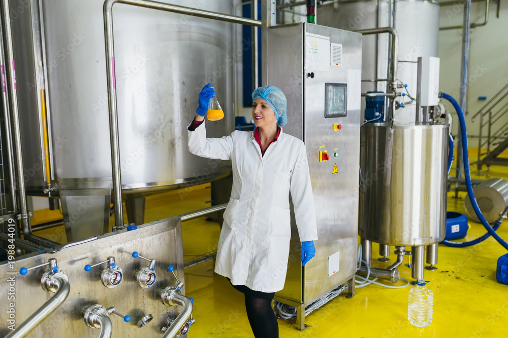 Worker at bottling factory checking juice quality. 