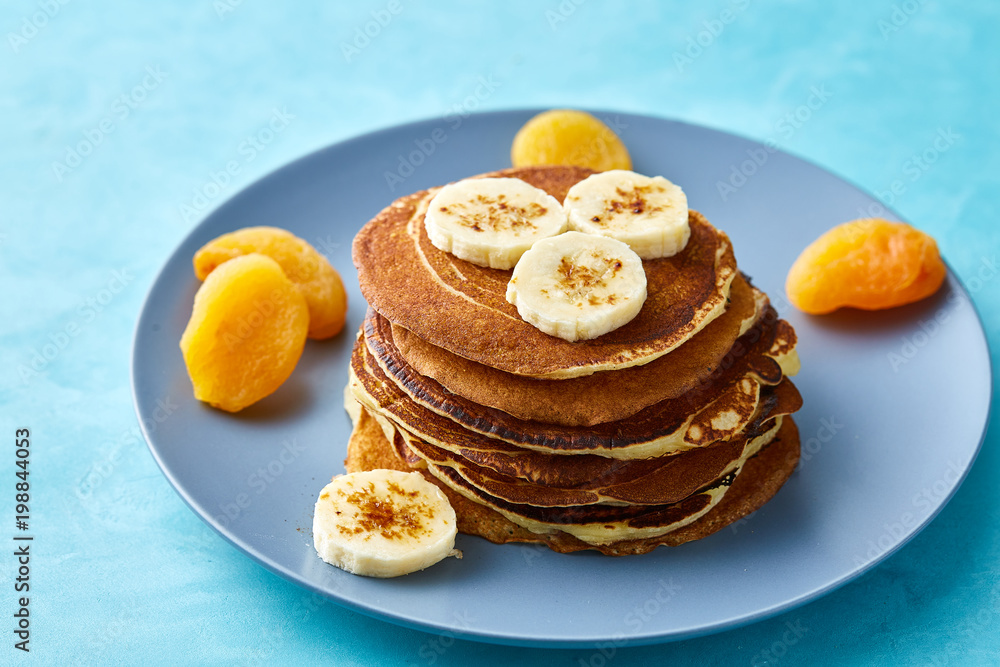 Pile of homemade pancakes with honey and walnuts on blue background, selective focus Pile of homemade pancakes with honey and walnuts on blue background, selective focus
