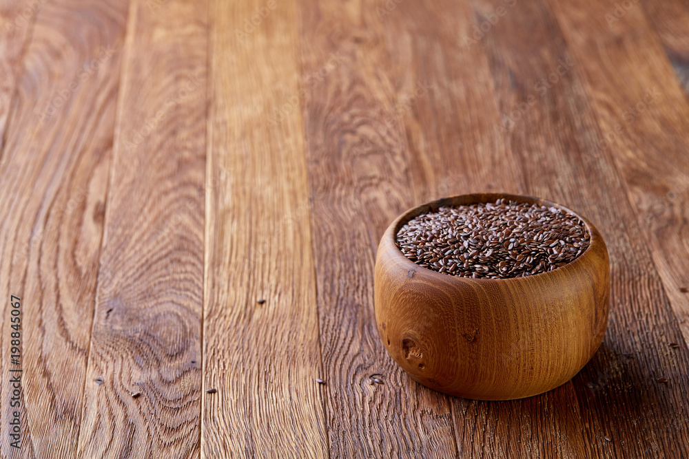 Flax seeds in a plate on wooden background, top view, close-up. Flax seeds in a plate on wooden background, top view, close-up.