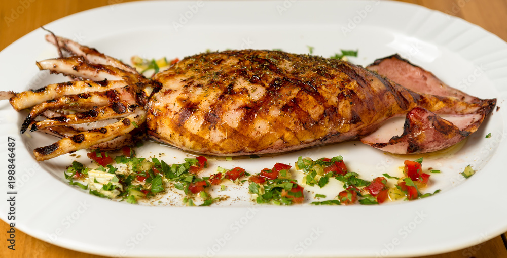 Grilled whole squid on a BBQ with Greek Spice. Top view. Wooden background. 