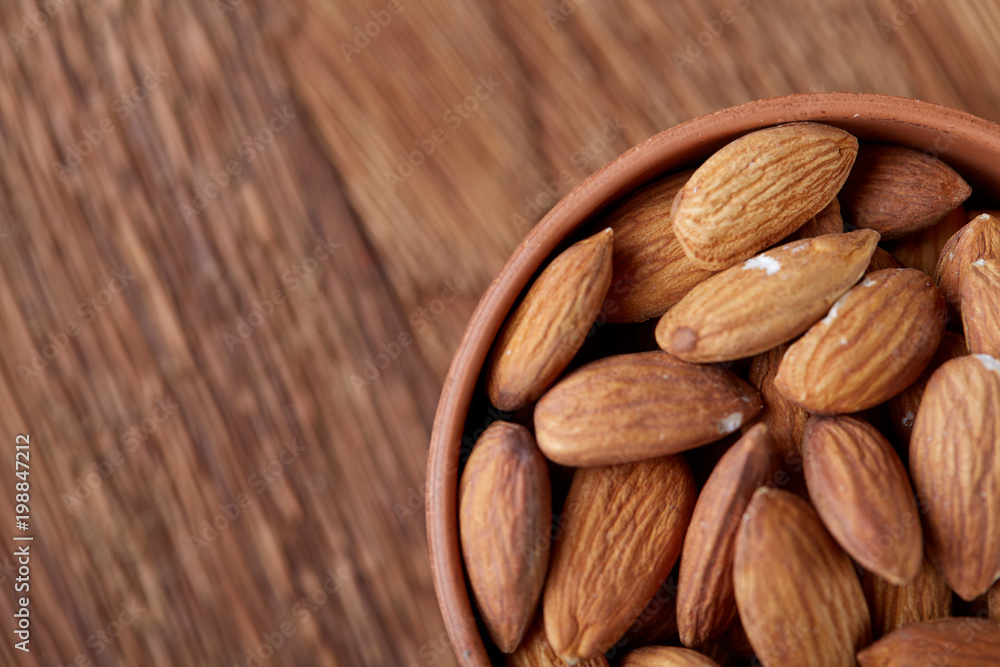 Ceramic bowl of almonds on wooden background, top view, close-up, selective focus. Ceramic bowl of almonds on wooden background, top view, close-up, selective focus.