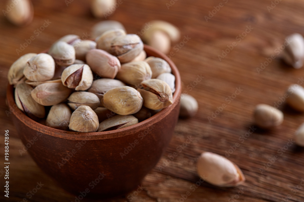 Almonds in brown bowl on wooden background, top view, selective focus. Almonds in brown bowl on wooden background, top view, selective focus.