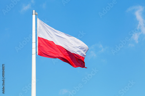 Polish national flag waving on the wind against blue cloudy sky