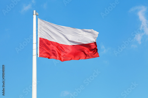 Polska flaga narodowa powiewająca na tle niebieskiego nieba photo