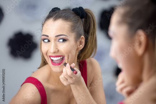 Beautiful young woman putting on make up