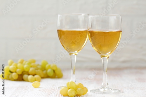 Glass of wine and grapes in the basket on a wooden table.
