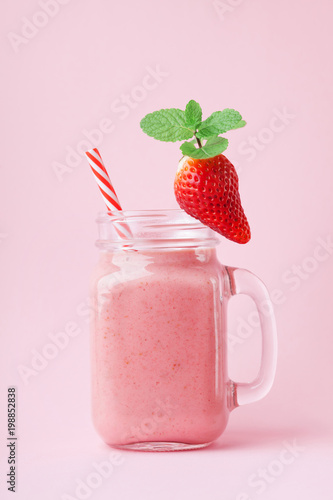 Fototapeta Strawberry smoothie or milkshake in mason jar decorated mint on pink pastel table