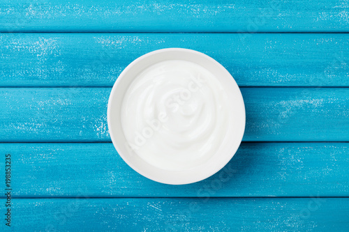 Diet greek yogurt in bowl on rustic wooden table top view.