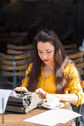 Writer female working in a cafe using a retro typewriter