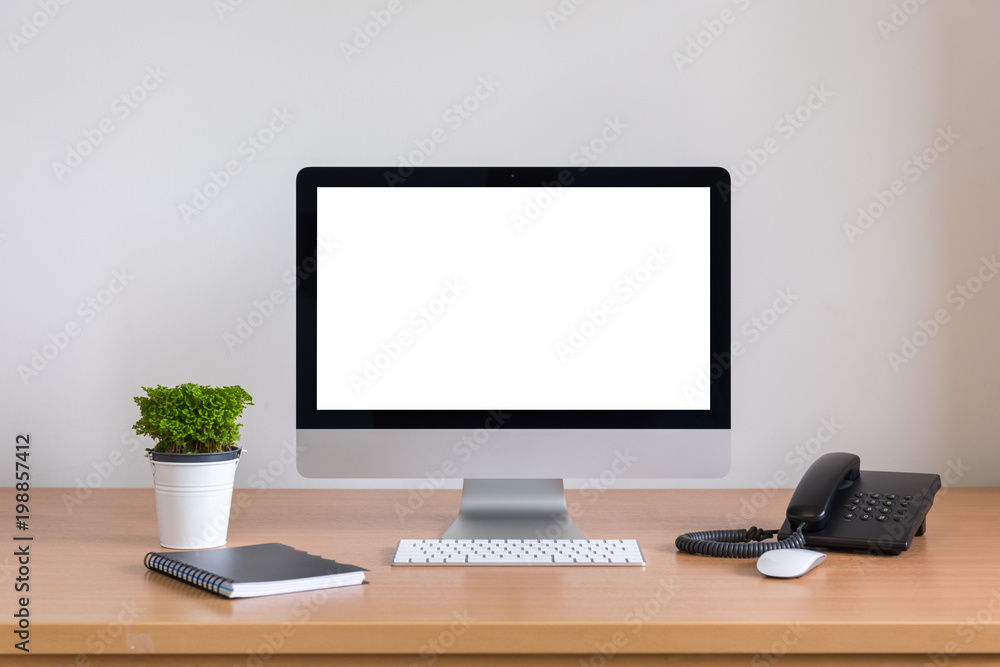 All in one computer, mouse, keyboard, phone, note book and tree vase on wooden table All in one computer, mouse, keyboard, phone, note book and tree vase on wooden table