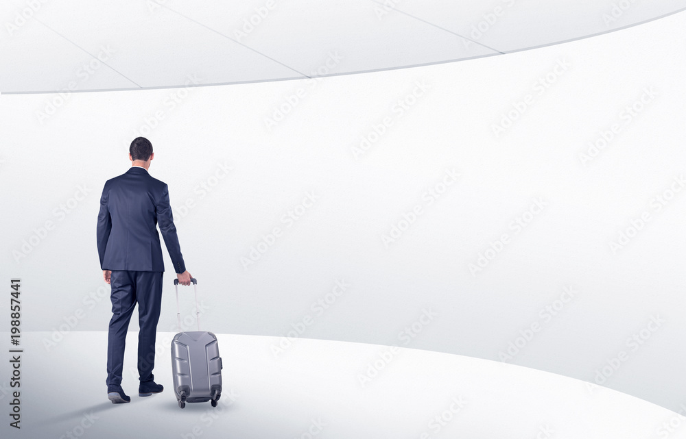 Businessman with back walking in a white waiting room with empty walls around
Businessman with back walking in a white waiting room with empty walls around