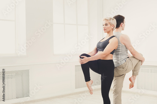 Young couple practicing yoga together in studio