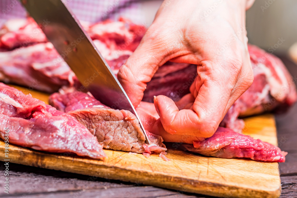 Female hands cut raw beef close