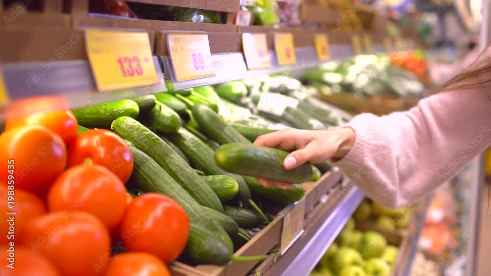 A woman in a supermarket on a vegetable shelf, buys vegetables and fruits. Woman chooses cucumbers. Slow motion, 4k A woman in a supermarket on a vegetable shelf, buys vegetables and fruits. Woman chooses cucumbers. Slow motion, 4k