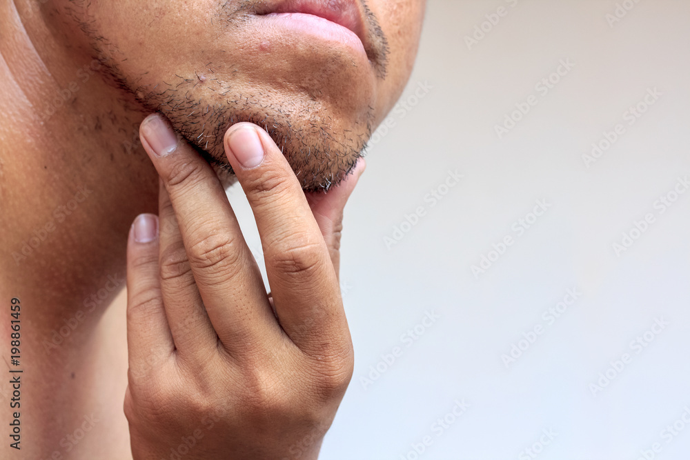 Close-up of young bearded man touching his beard on white background Close-up of young bearded man touching his beard on white background