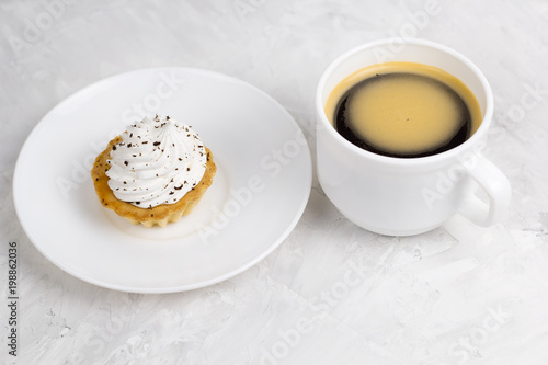 cupcake with cream decorated with chocolate chips and coffee cup concrete background