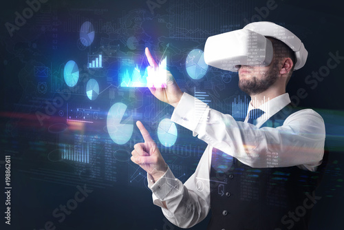 Elegant businessman in DJI goggles handling 3D reports and charts around him 