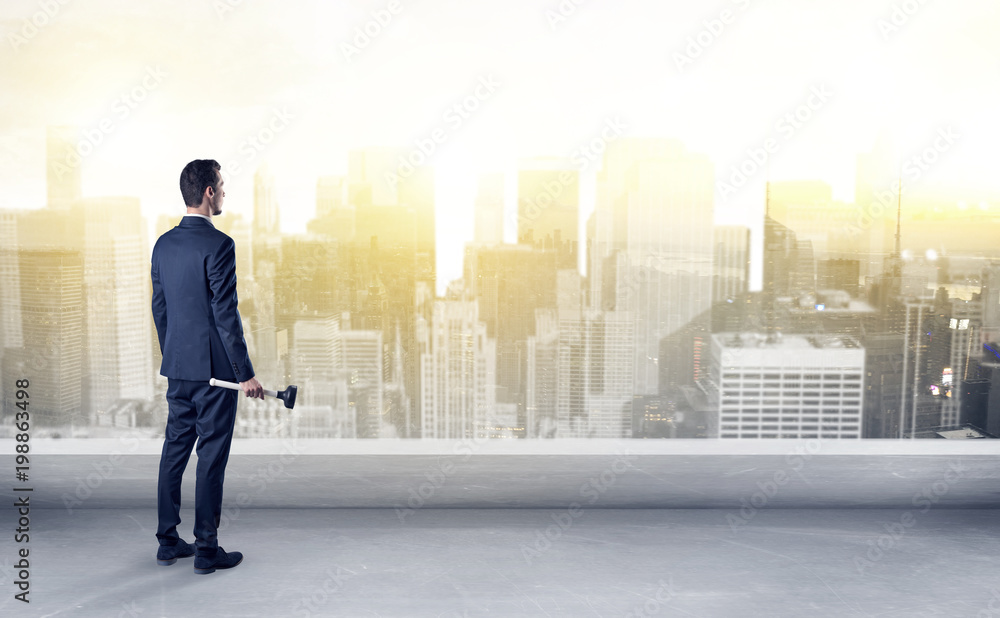 Businessman standing with his back on a roof with objects in his hand
