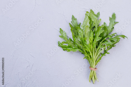 Bunch of fresh arugula on textured background. Branches of organic rucola and copy space.