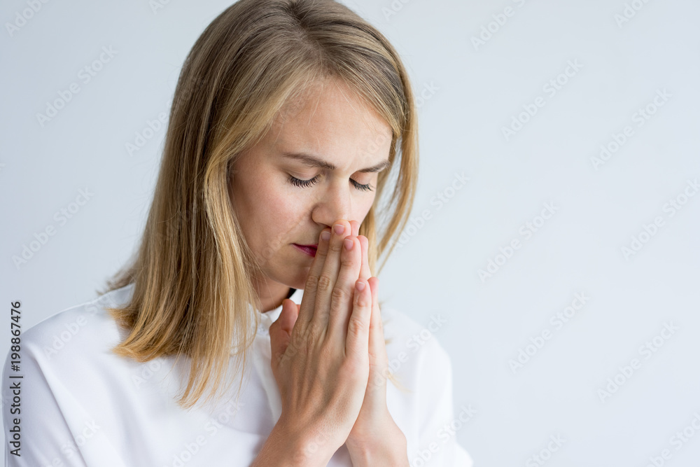 Portrait of concentrated young Caucasian woman wearing white shirt praying. Young business assistant with closed eyes thinking how to solve problem. Spirituality, concentration concept Portrait of concentrated young Caucasian woman wearing white shirt praying. Young business assistant with closed eyes thinking how to solve problem. Spirituality, concentration concept