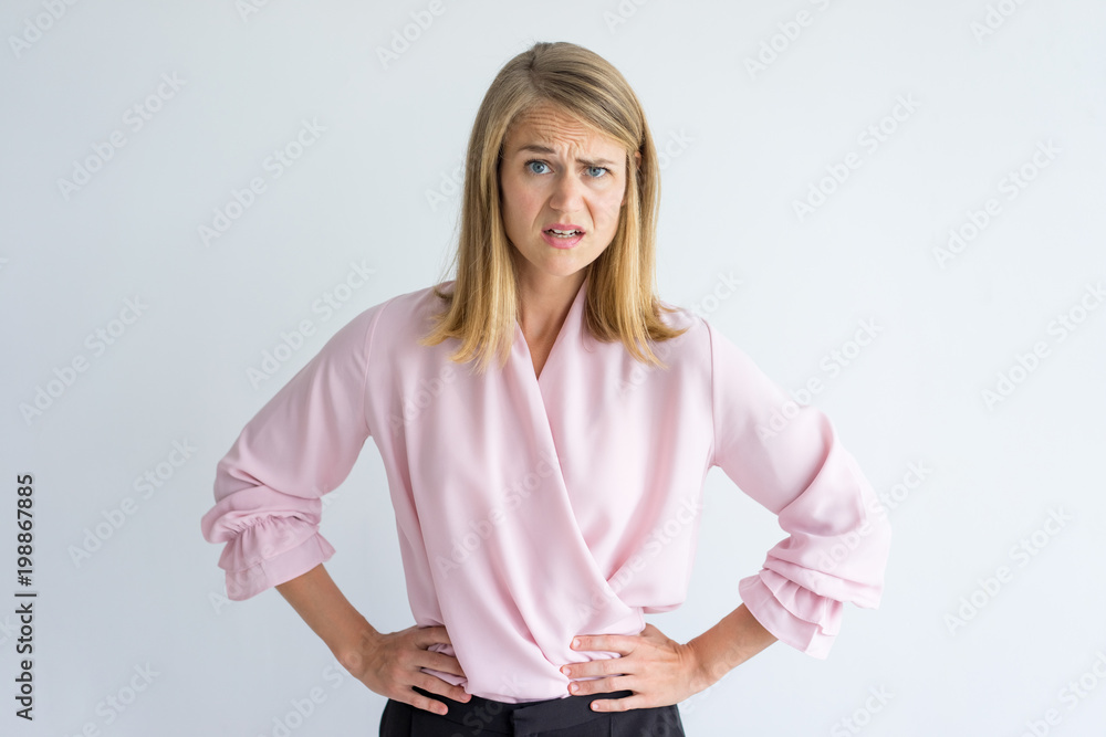 © Mangostar - Portrait of young Caucasian businesswoman wearing pink blouse standing with hands on waist displeased at some rude behavior. Irritation, misunderstanding concept © Mangostar - Portrait of young Caucasian businesswoman wearing pink blouse standing with hands on waist displeased at some rude behavior. Irritation, misunderstanding concept