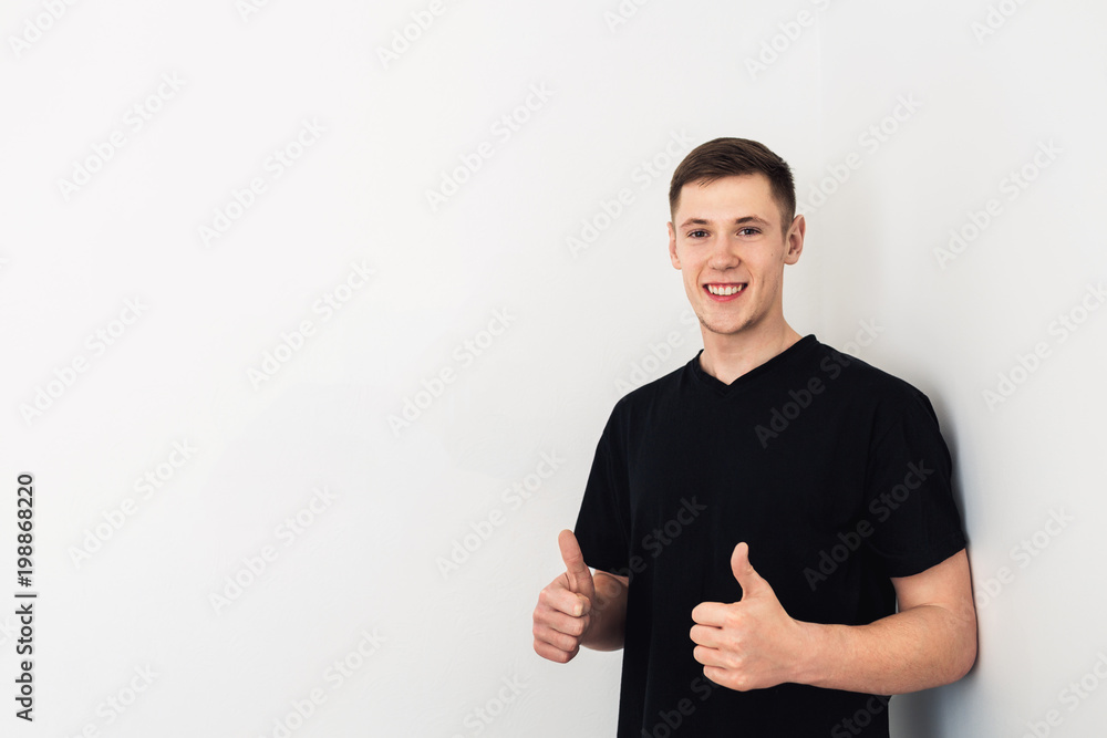 Portrait of handsome guy in black T-shirt posing against a white wall. Copy space Portrait of handsome guy in black T-shirt posing against a white wall. Copy space