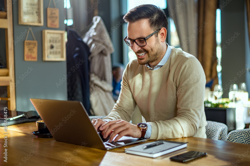 Young businessman working on laptop computer in modern cafe