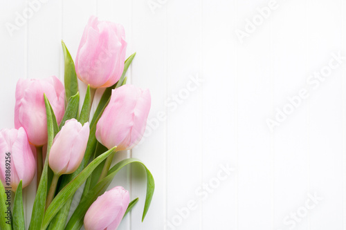 Fototapeta Naklejka Na Ścianę i Meble -  Fresh pink tulip flowers bouquet on shelf in front of wooden wall.