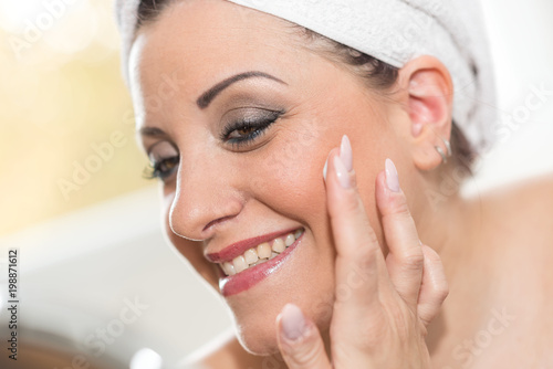 Portrait of smiling young woman applying moisturizing cream