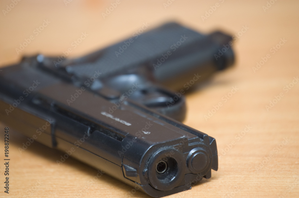 pistol on brown table close-up pistol on brown table close-up