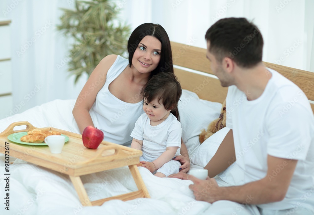 Family taking the breakfast on the bed in the bedroom