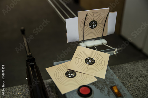 Air gun and three targets with bullet holes in it at shooting range