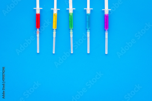 Vaccination, immunization. Syringe with colored medicament on blue background top view copy space