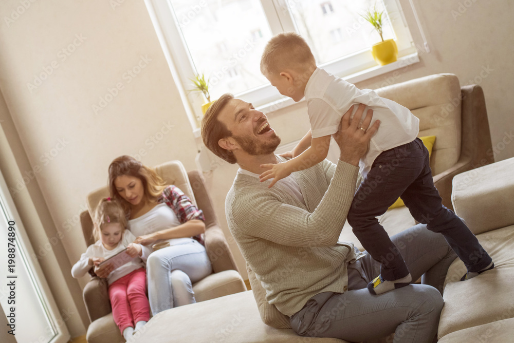 Parents with children playing together and having fun in living room
