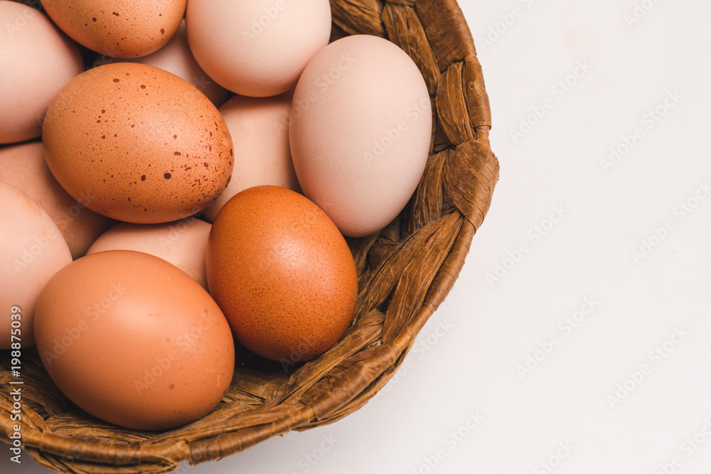 Colored chicken eggs in a wicker brown basket on a light background Colored chicken eggs in a wicker brown basket on a light background