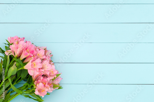 Beautiful pink alstroemerias on a turquoise woodent planks as a background  top flat view  copy space 