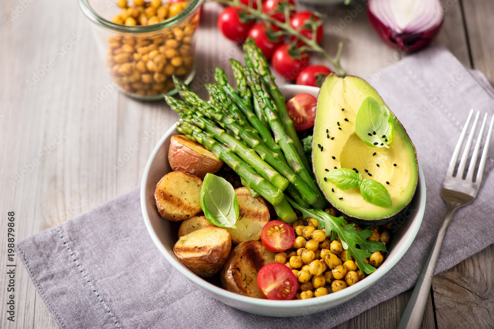 Healthy dinner with baked potatoes, green asparagus and spicy chickpeas, avocado, arugula, vegan, vegetarian food Healthy dinner with baked potatoes, green asparagus and spicy chickpeas, avocado, arugula, vegan, vegetarian food