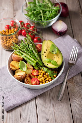 Healthy dinner with baked potatoes, green asparagus and spicy chickpeas, avocado, arugula, vegan, vegetarian food