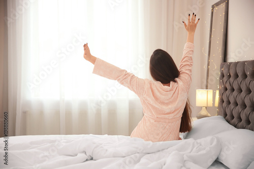 Young woman stretching on bed in hotel room