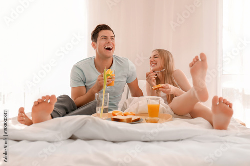 Young lovely couple having breakfast on bed