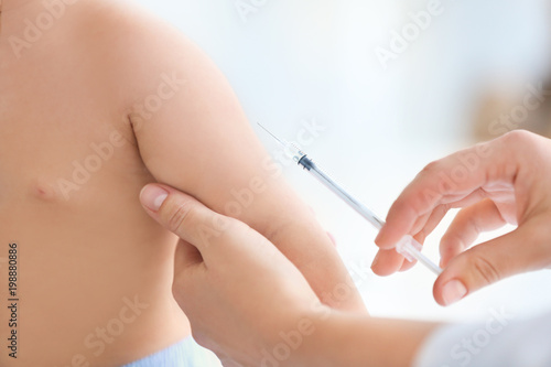 Doctor vaccinating baby in clinic, closeup